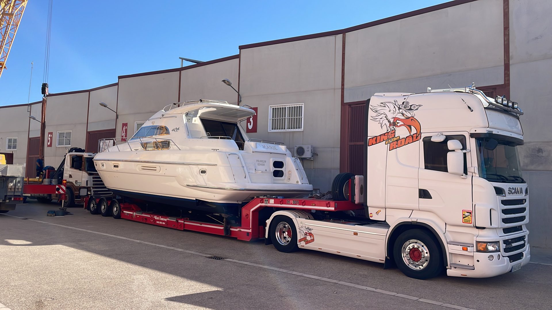 Ein weißes Boot wird auf einen Lastwagen geladen.
